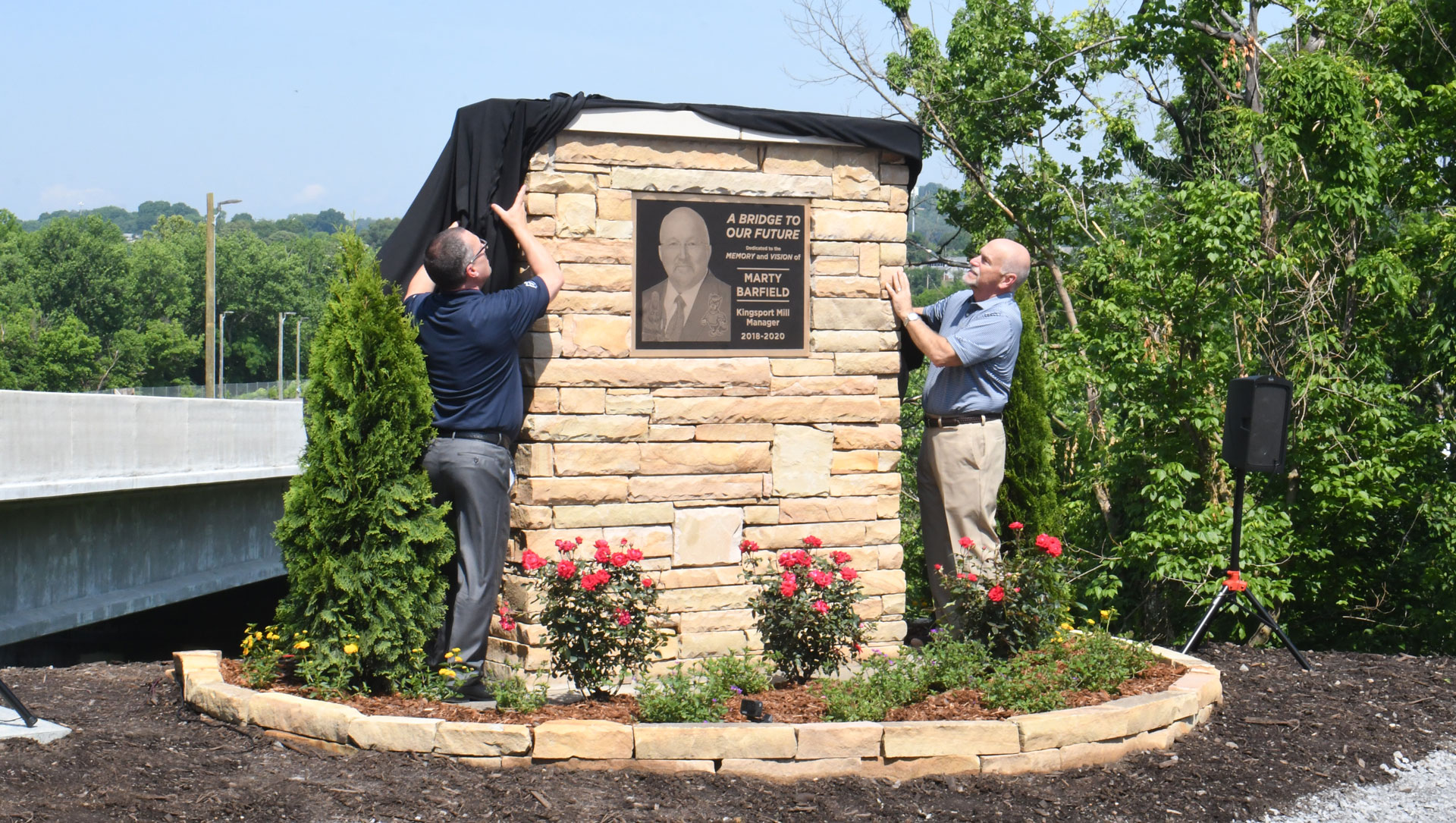 Troy Wilson, mill manager, and Charlie Floyd, vice president of packaging capital, unveil the Marty Barfield memorial on Friday, May 20, 2022.