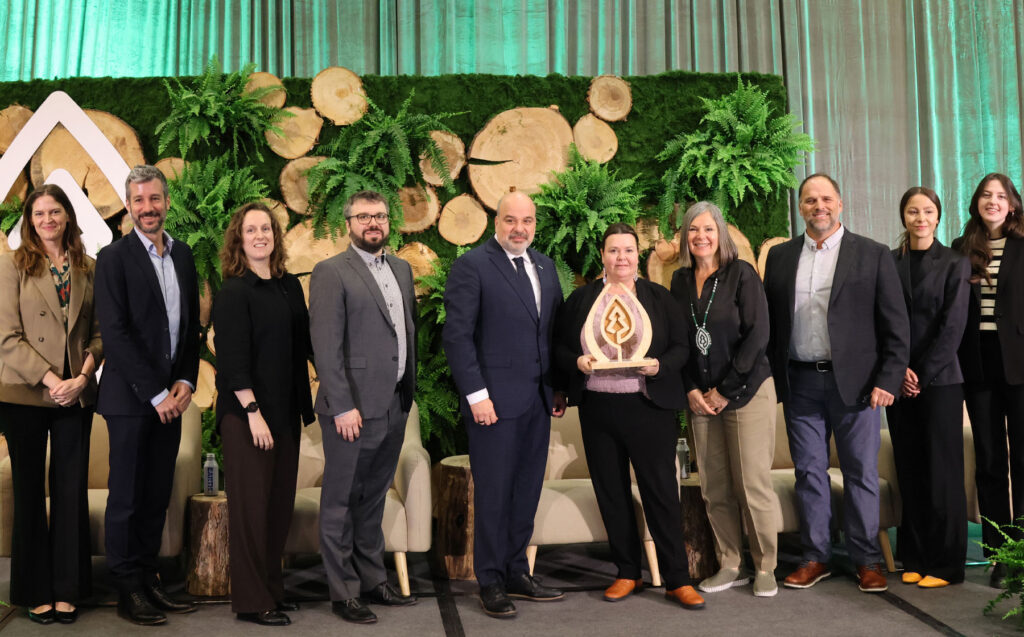 Group photo of Domtar team members receiving the 2026 SFI Leadership in Conservation Award on stage in front of a forest-themed backdrop.