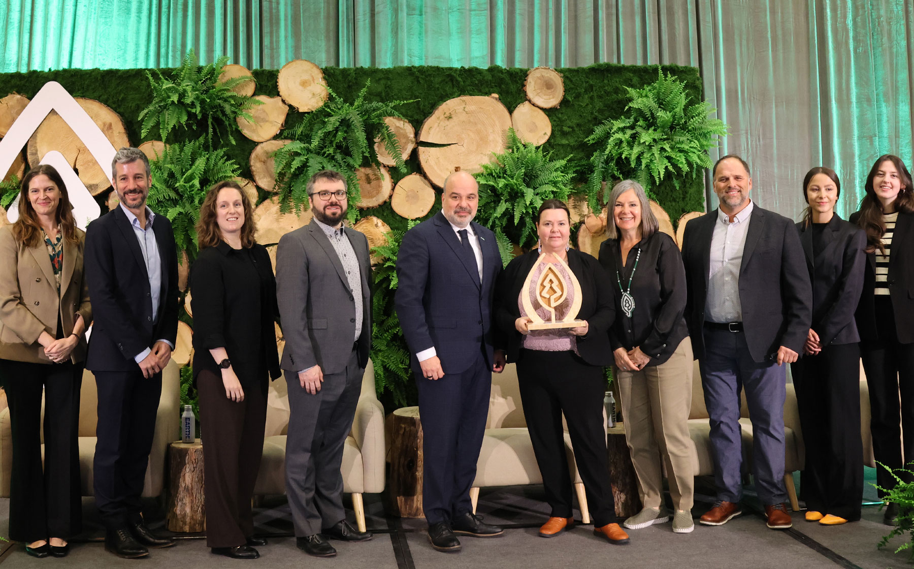 Group photo of Domtar team members receiving the 2026 SFI Leadership in Conservation Award on stage in front of a forest-themed backdrop.